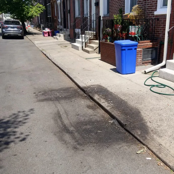 Empty driveway after fire-damaged junk car removal service in Philadelphia rowhouse street