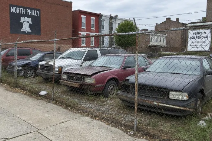 Tow truck clearing multiple junk vehicles from a North Philadelphia lot